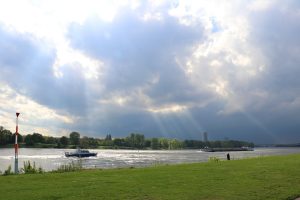 Sonnenstrahlen finden ihren Weg durch die Gewitterwolken am Rhein